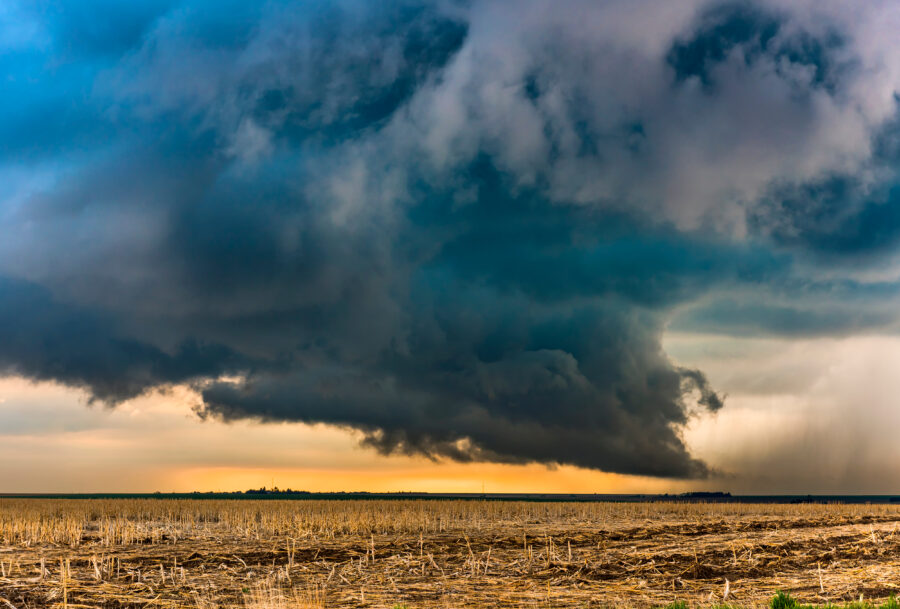 Large, dark tornadic cloud over farm field